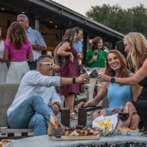 A group of people enjoy drinks and snacks together outdoors at a social gathering.